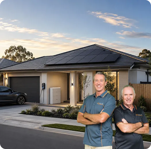 Allan Border and Glenn McGrath standing in front of a modern Greater Melbourne home with black monocrystalline solar panels and an outdoor home battery system.